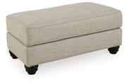 Ashley Furniture Asanti Ottoman featuring a plush fabric surface and sturdy wooden legs in a contemporary design.